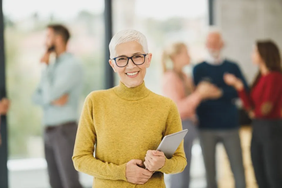 Una responsable de recursos humanos con una tableta, con su equipo al fondo